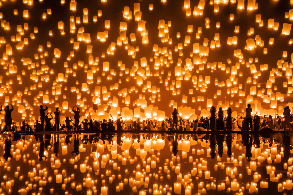 People release hundreds of floating lanterns into the sky, and they are reflecting in the surrounding waters.