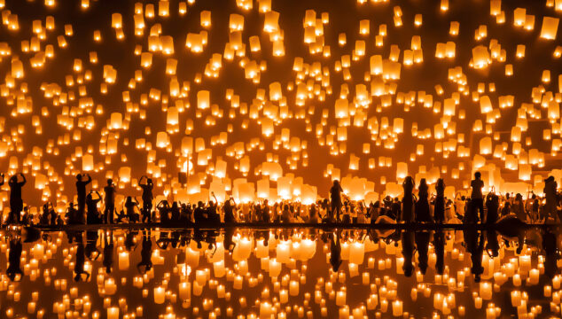 People release hundreds of floating lanterns into the sky, and they are reflecting in the surrounding waters.